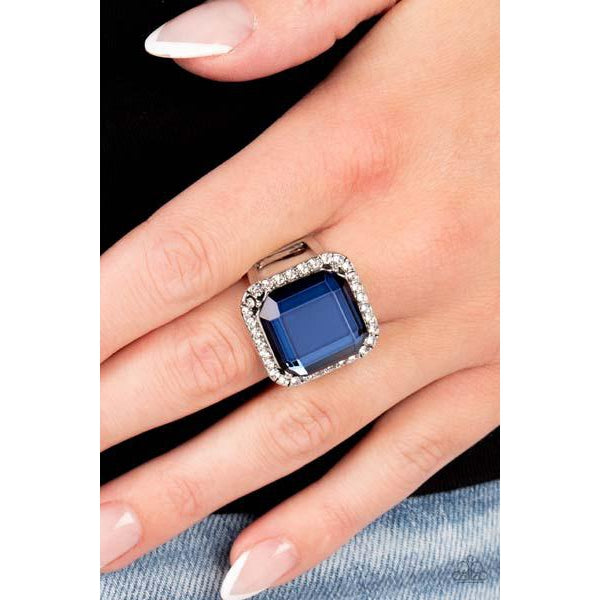 Paparazzi Slow Burn - Blue Stretch Ring  A lavish square Skydiver gem, encased in a border of dainty white rhinestones, makes a head-turning centerpiece as it gleams with an industrial edge atop the finger. Features a stretchy band for a flexible fit.